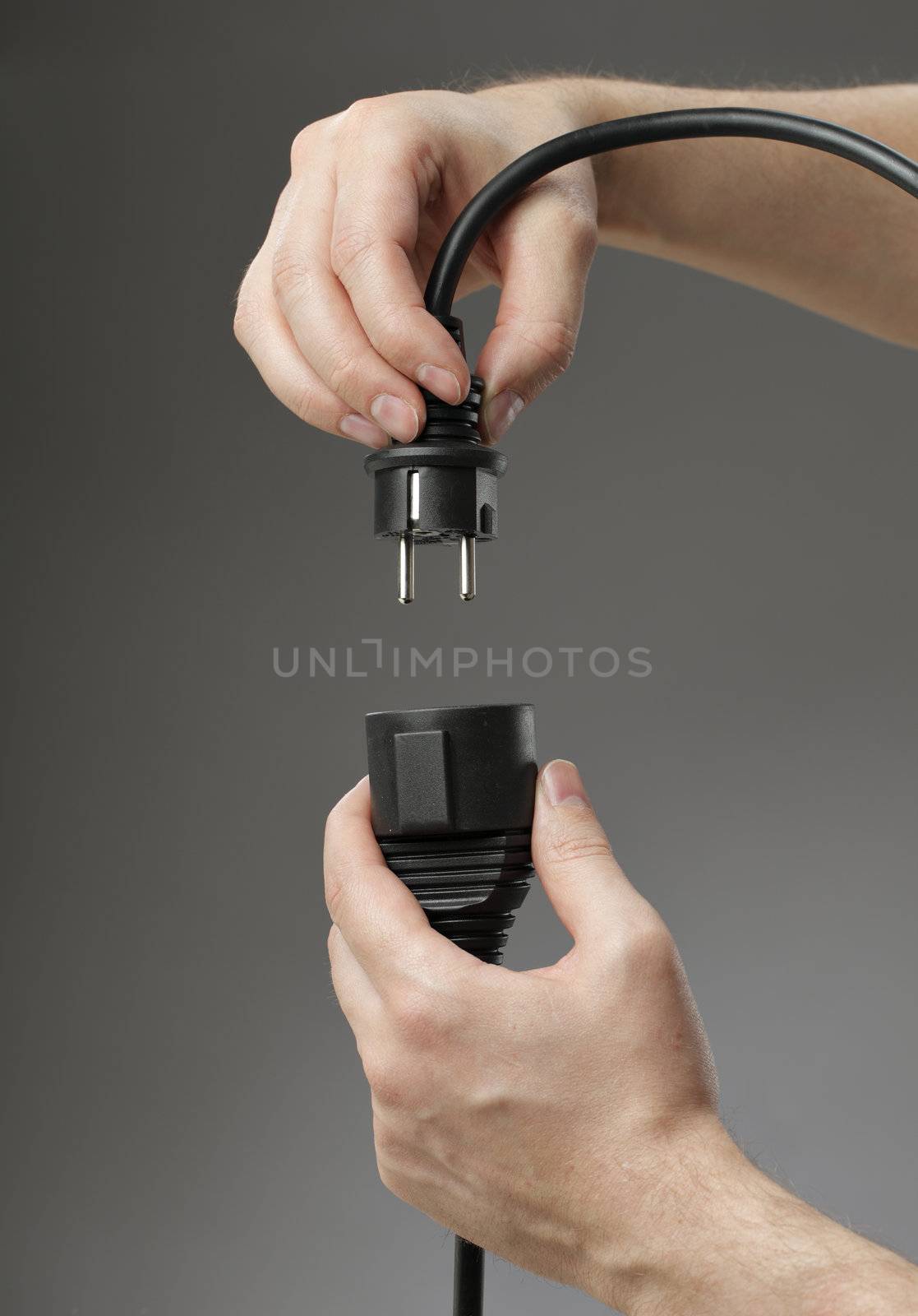 Hand plugging a black european extension cord