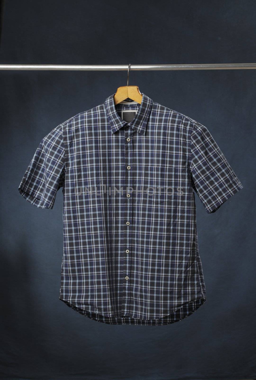 A new men's blue plaid cotton shirt hanging on a hanger.