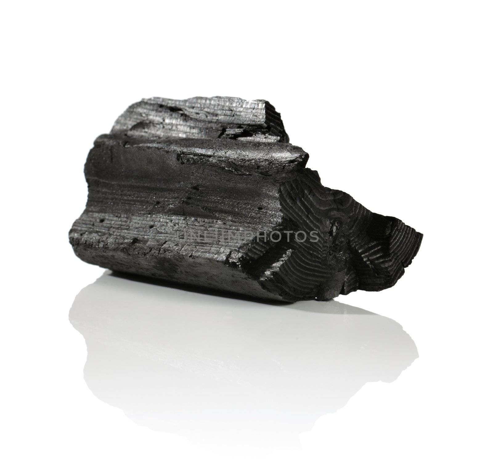 A Lump of charcoal made of wood on reflective background