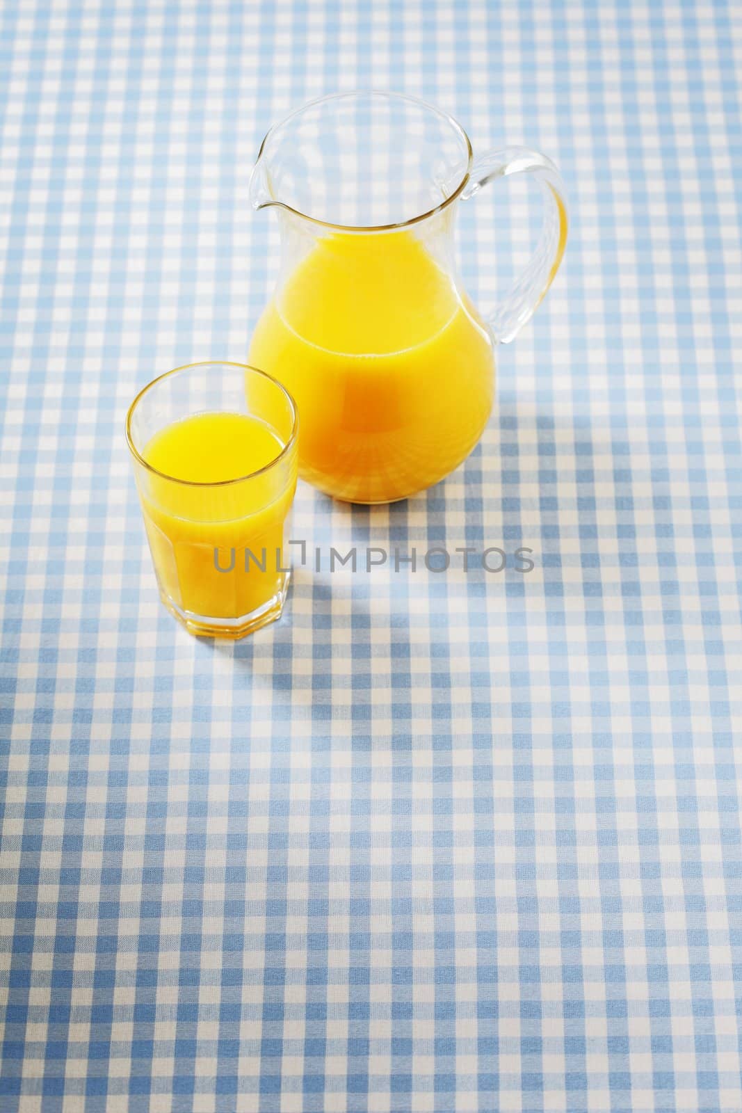 Glass of juice with a pitcher on plaid tablecloth