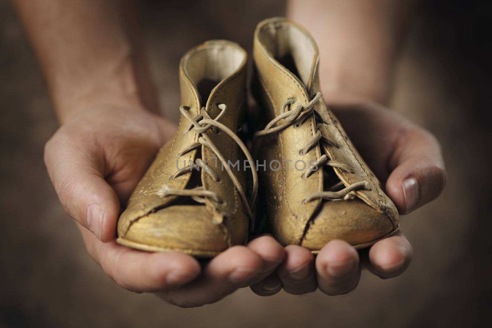 Man holding a pair of old baby shoes