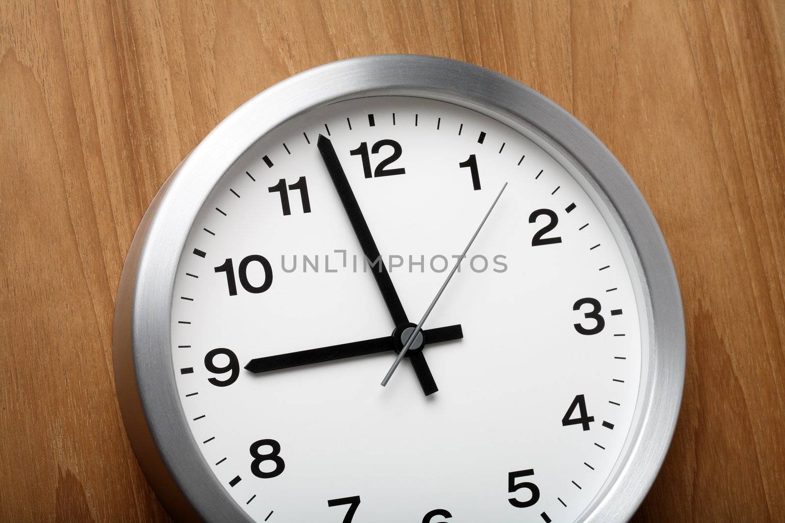 The aluminum wall clock is almost nine.