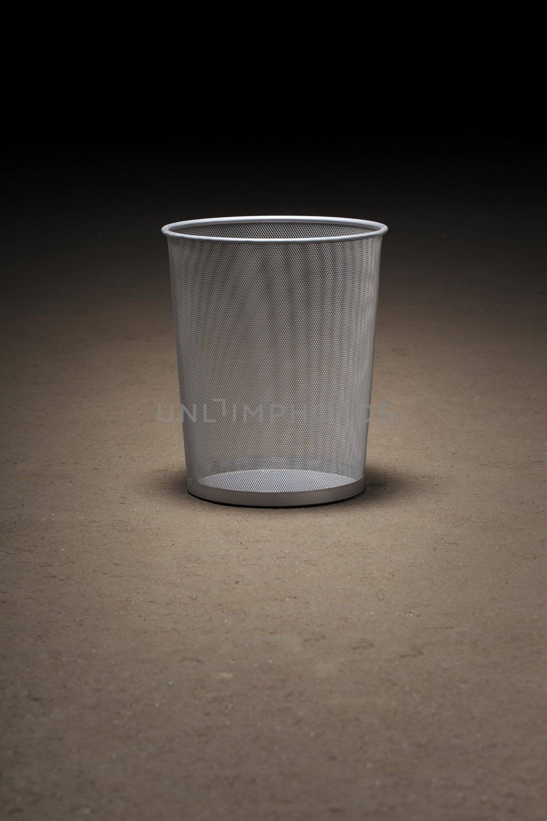 Empty wastepaper basket on dirty concrete floor