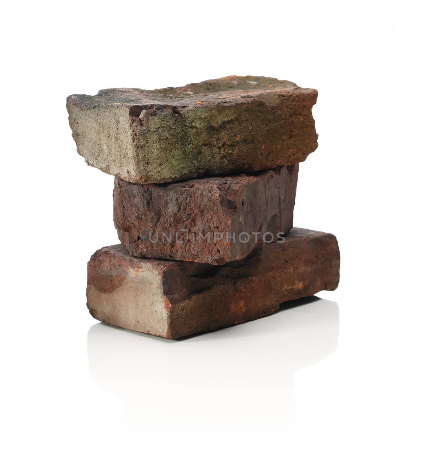 Three old bricks, stacked on a reflective background