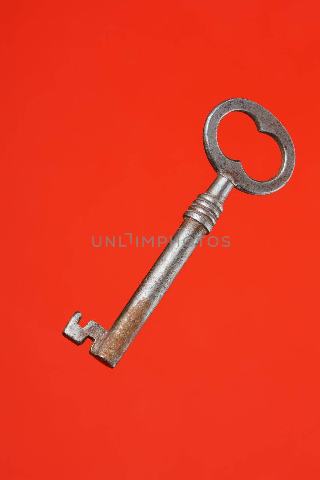 Old metallic key on red background