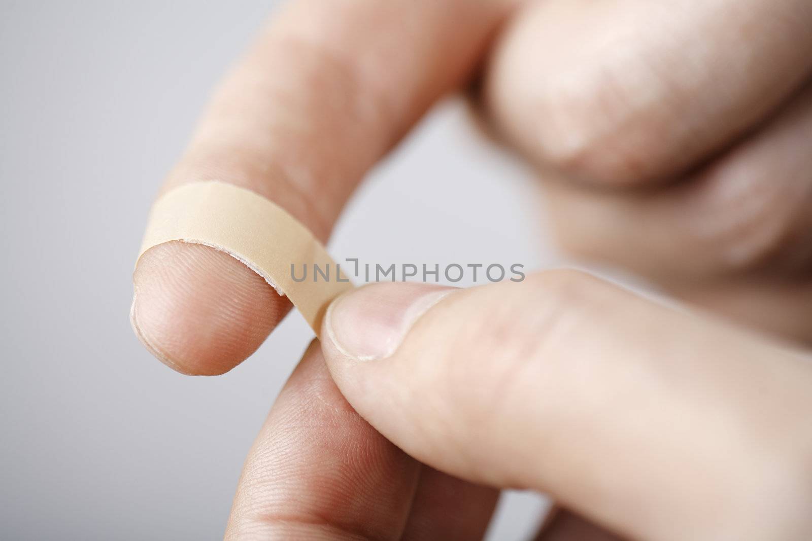 Putting a small adhesive,bandage on a finger. Very short depth-of-field.