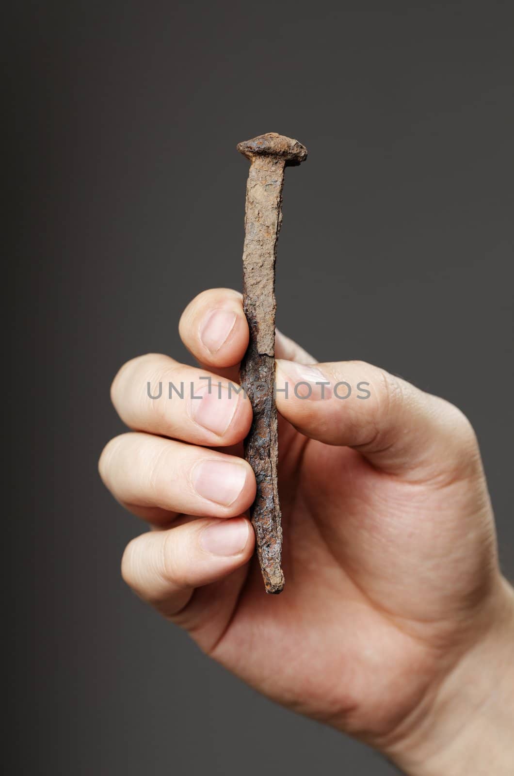 Man holding an old rusty nail in his hand