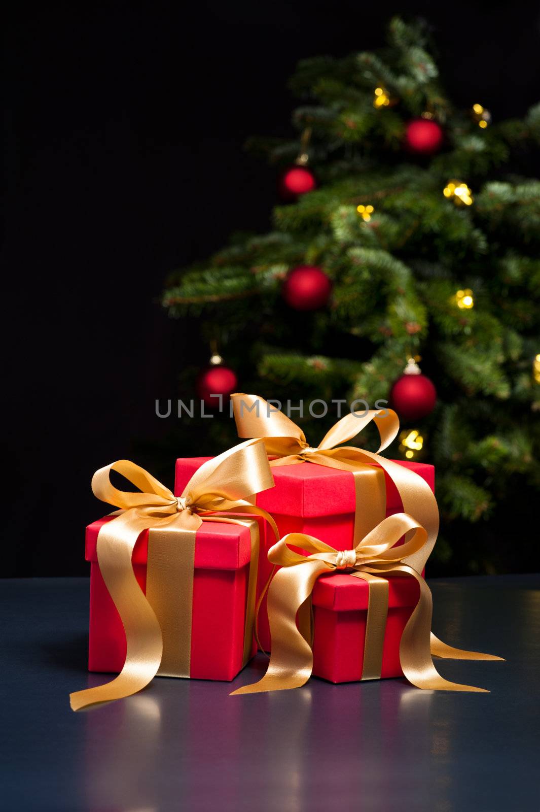 Three presents with gold ribbon in an elegant Christmas setting