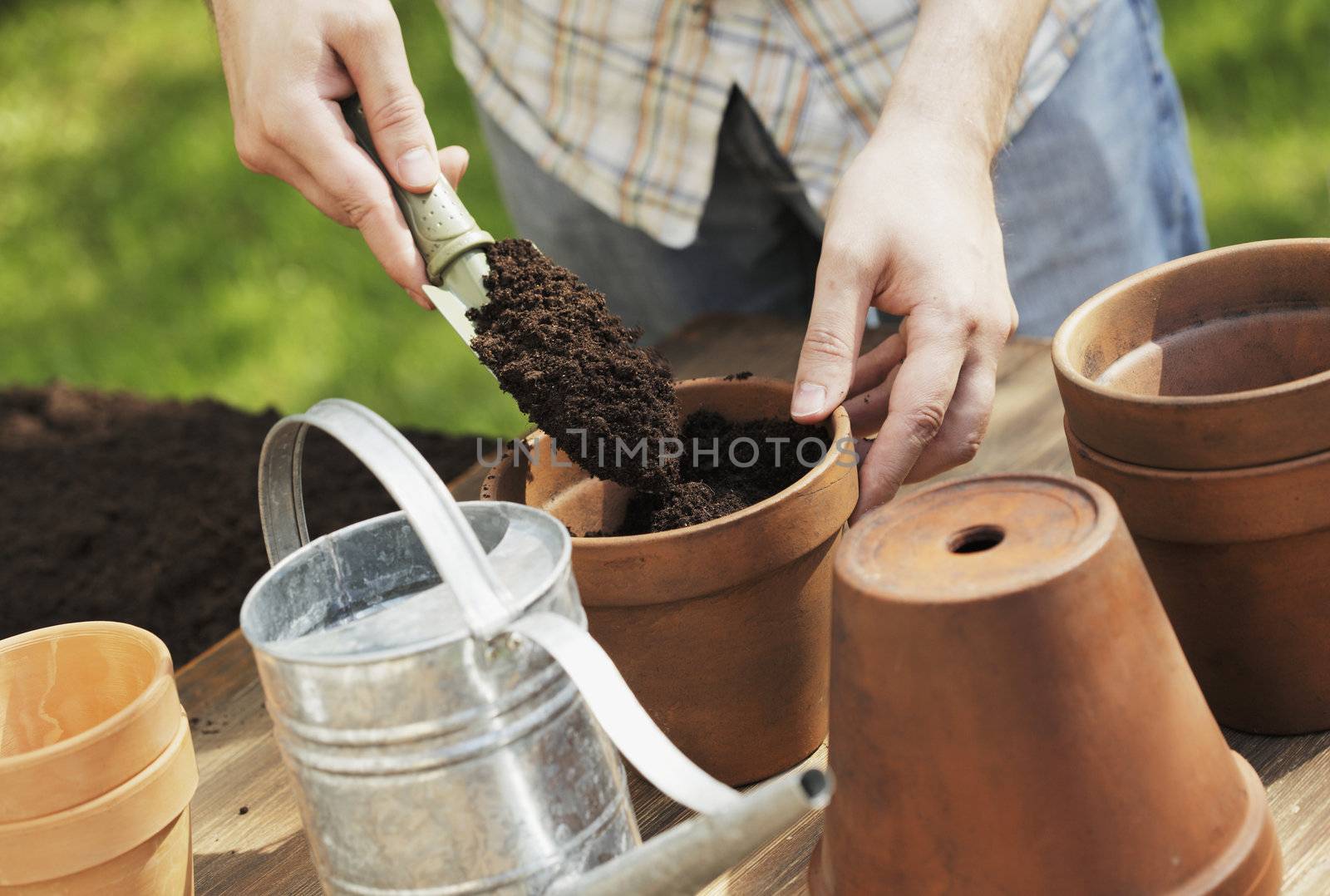 Hands putting soil in clay pot with a small shovel