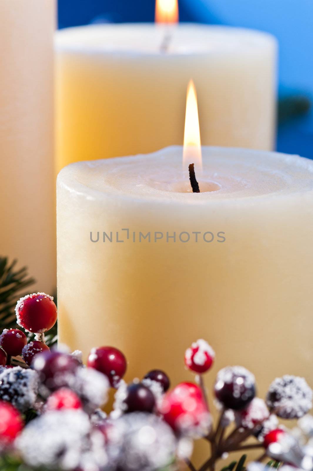 Three candles in front of an blue background, an advent flower arrangement for advent and Christmas