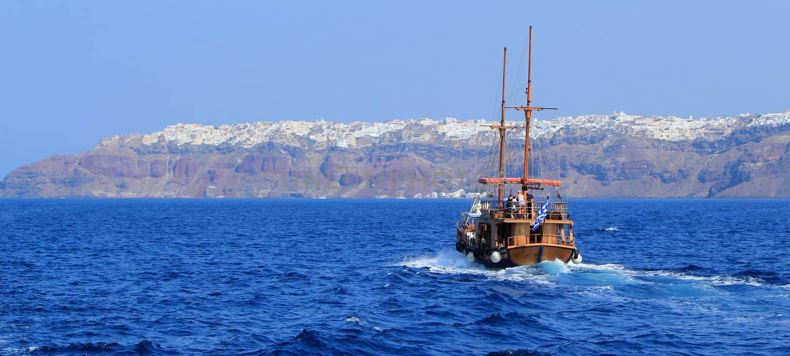 Panoramic view of an old tourist boat going to Oia village on the cliff at Santorini, Greece