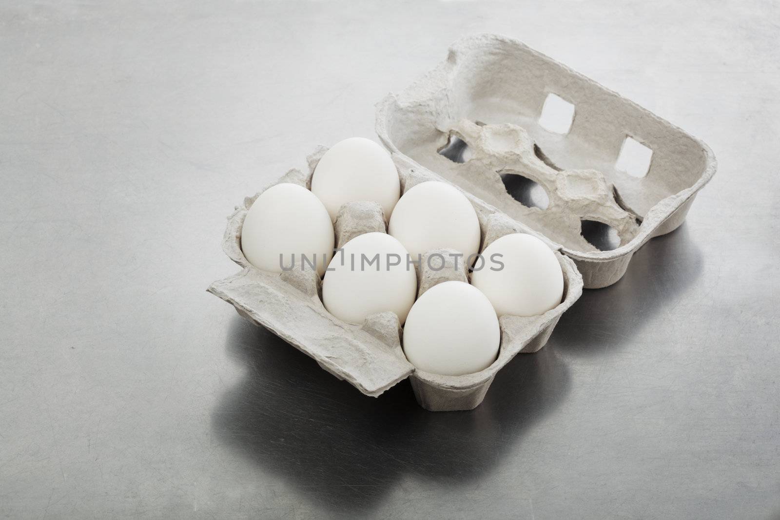 Six eggs in an egg carton on metallic background