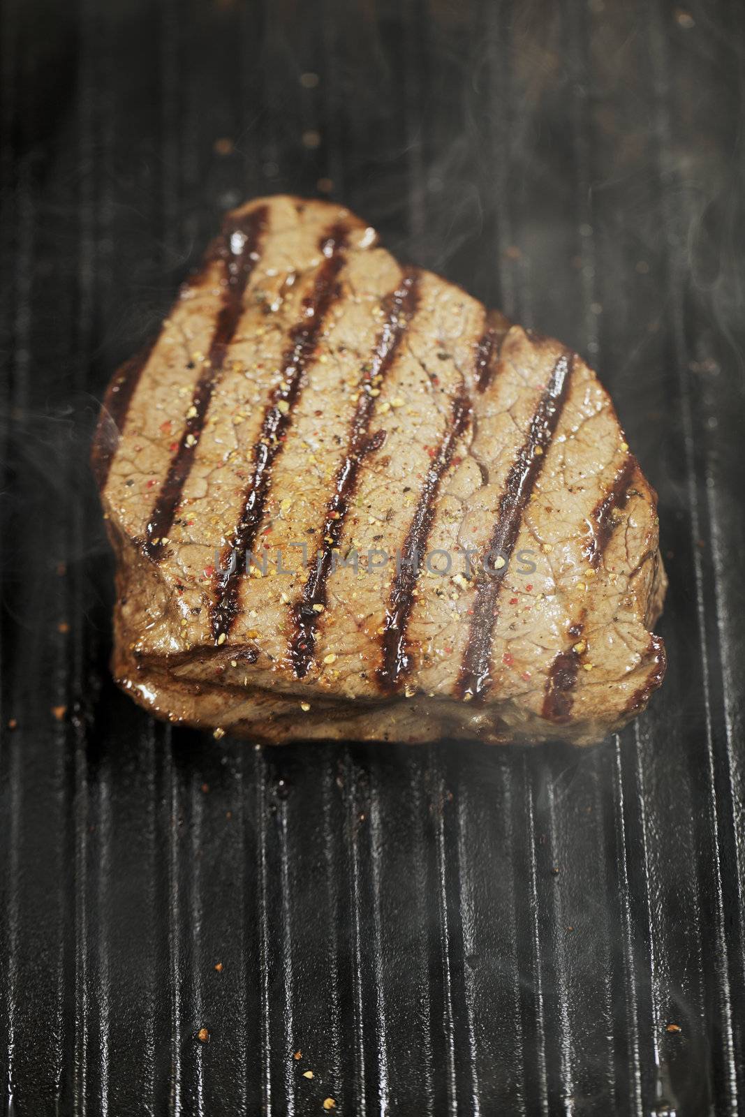 Beef tenderloin steak with pepper on a grill pan.