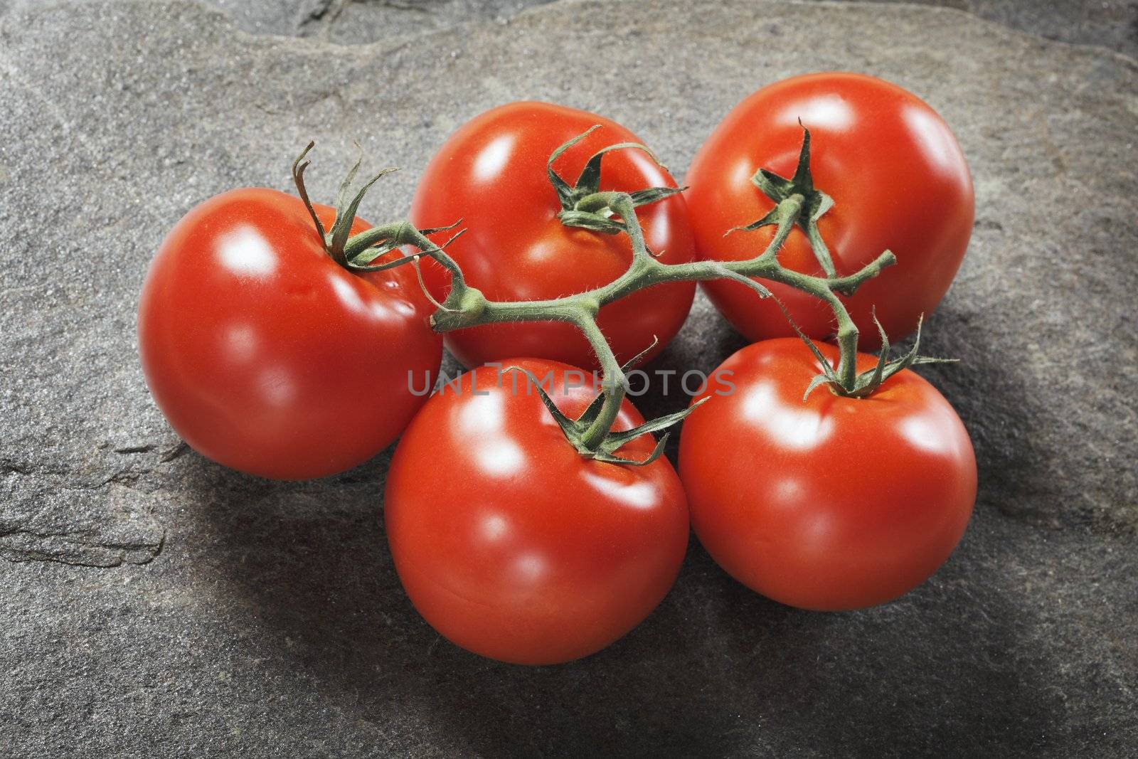 Fresh ripe tomatoes on stone background