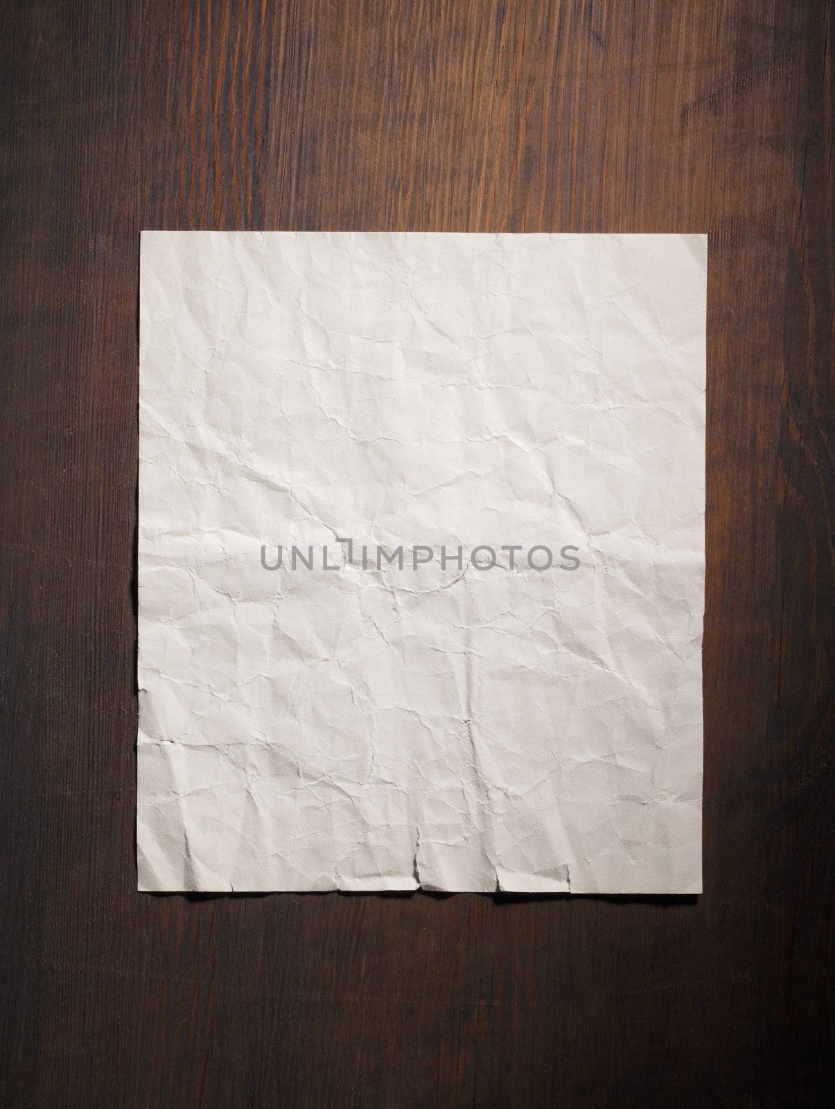 Old wrinkled blank paper on wooden background.