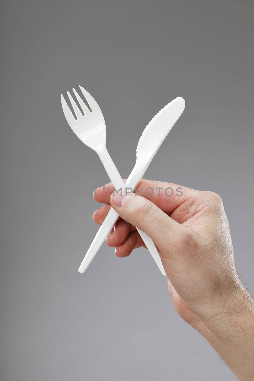Hand holding white disposable plastic fork and knife