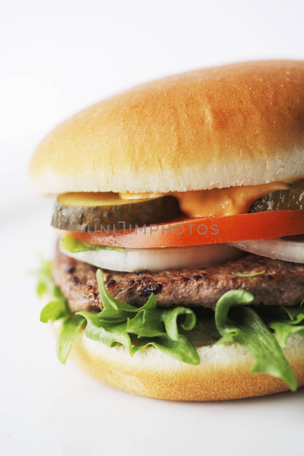 Hamburger with onion rings, tomato, lettuce and pickled cucumber