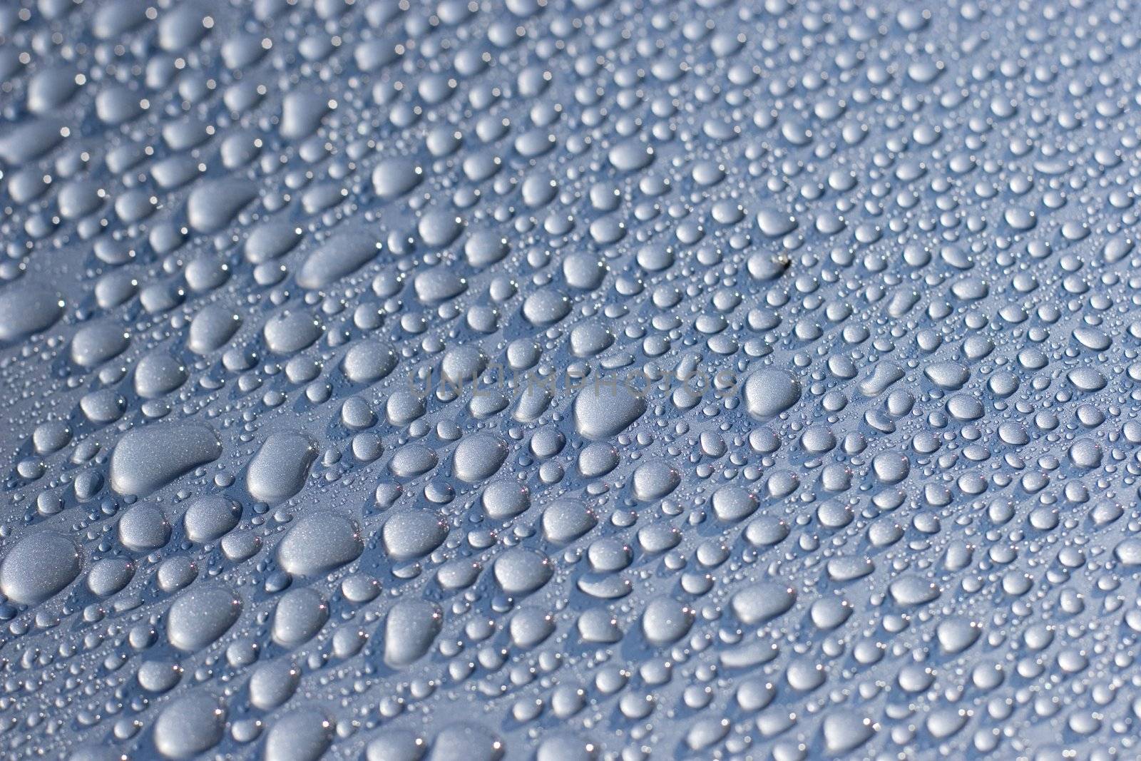 Water droplets on a car. Short depth-of-field, some sharpness in the middle and bottom left.