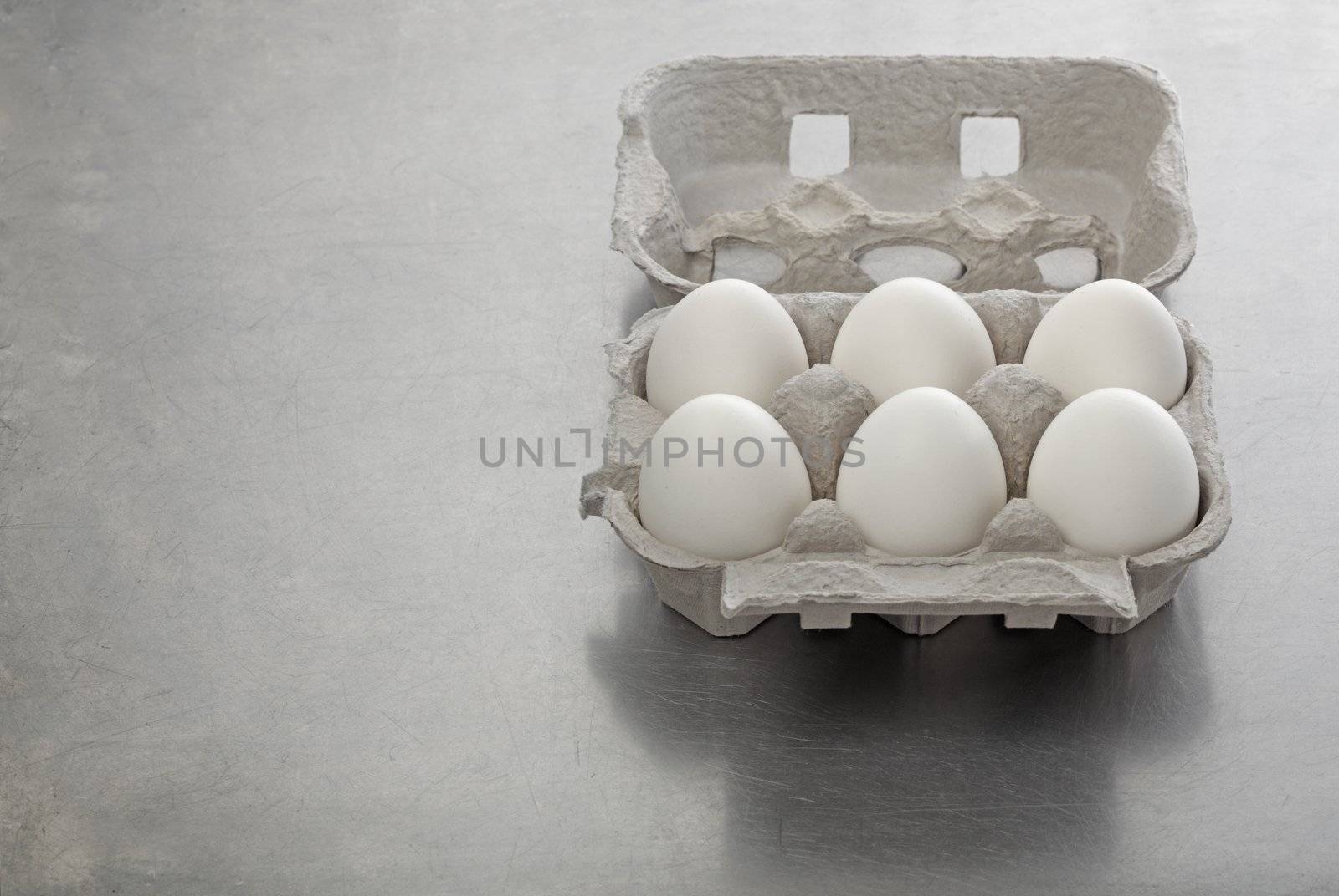 Six eggs in a cardboard carton on steel background