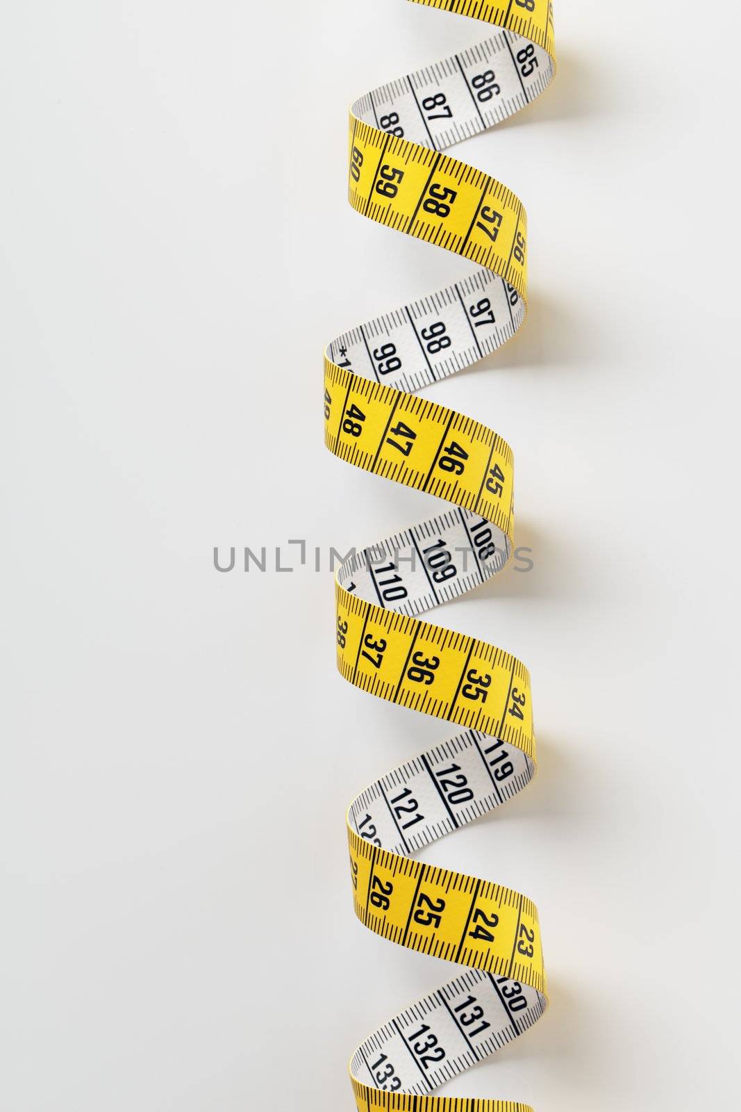 Yellow tape measure on light grey background