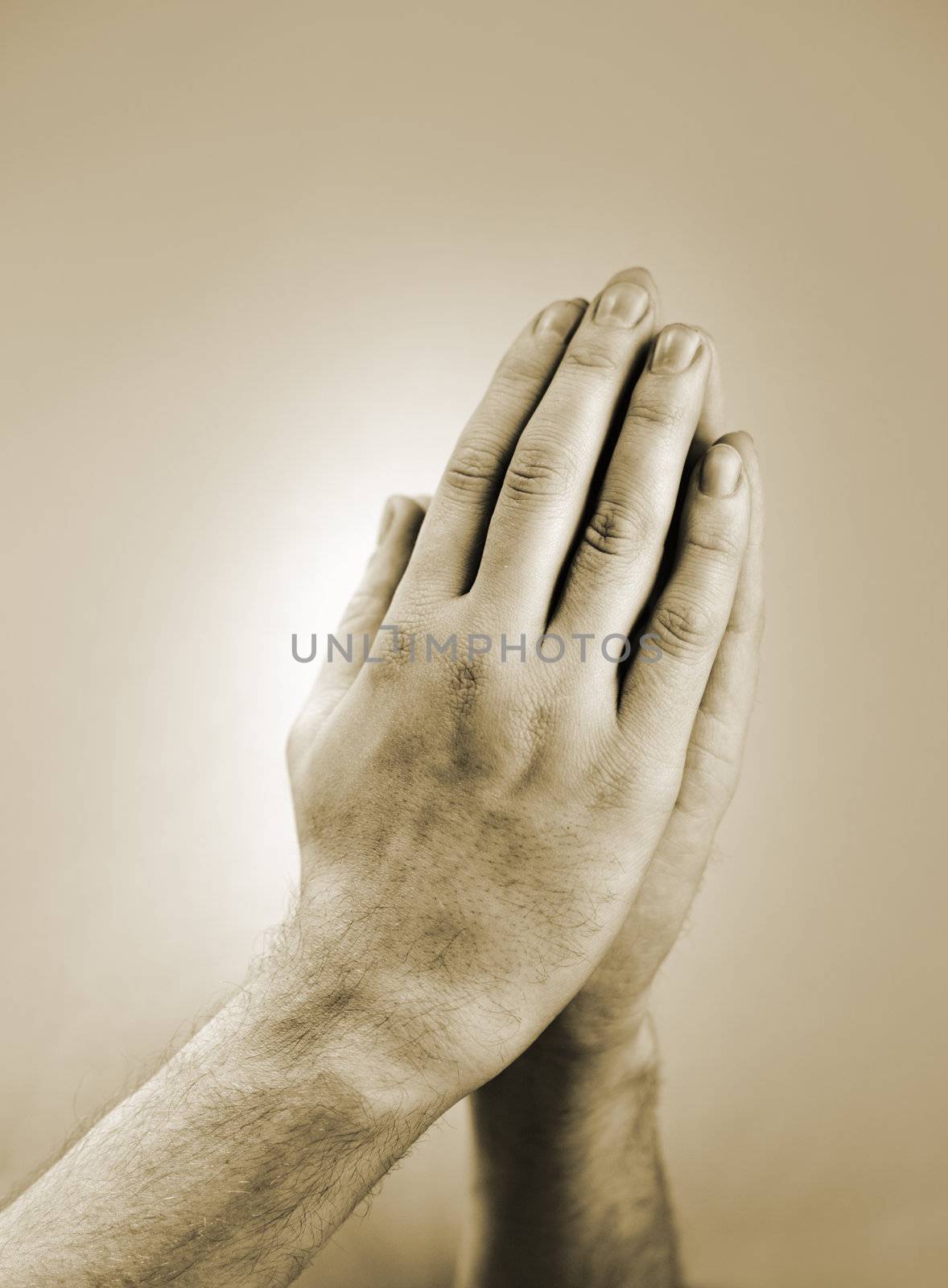 Sepia toned photograph of hand clasped in prayer