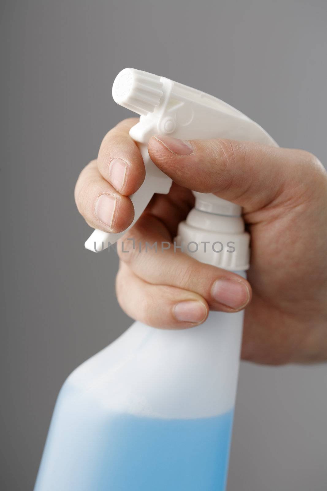 Hand holding a plastic spray bottle filled with blue liquid