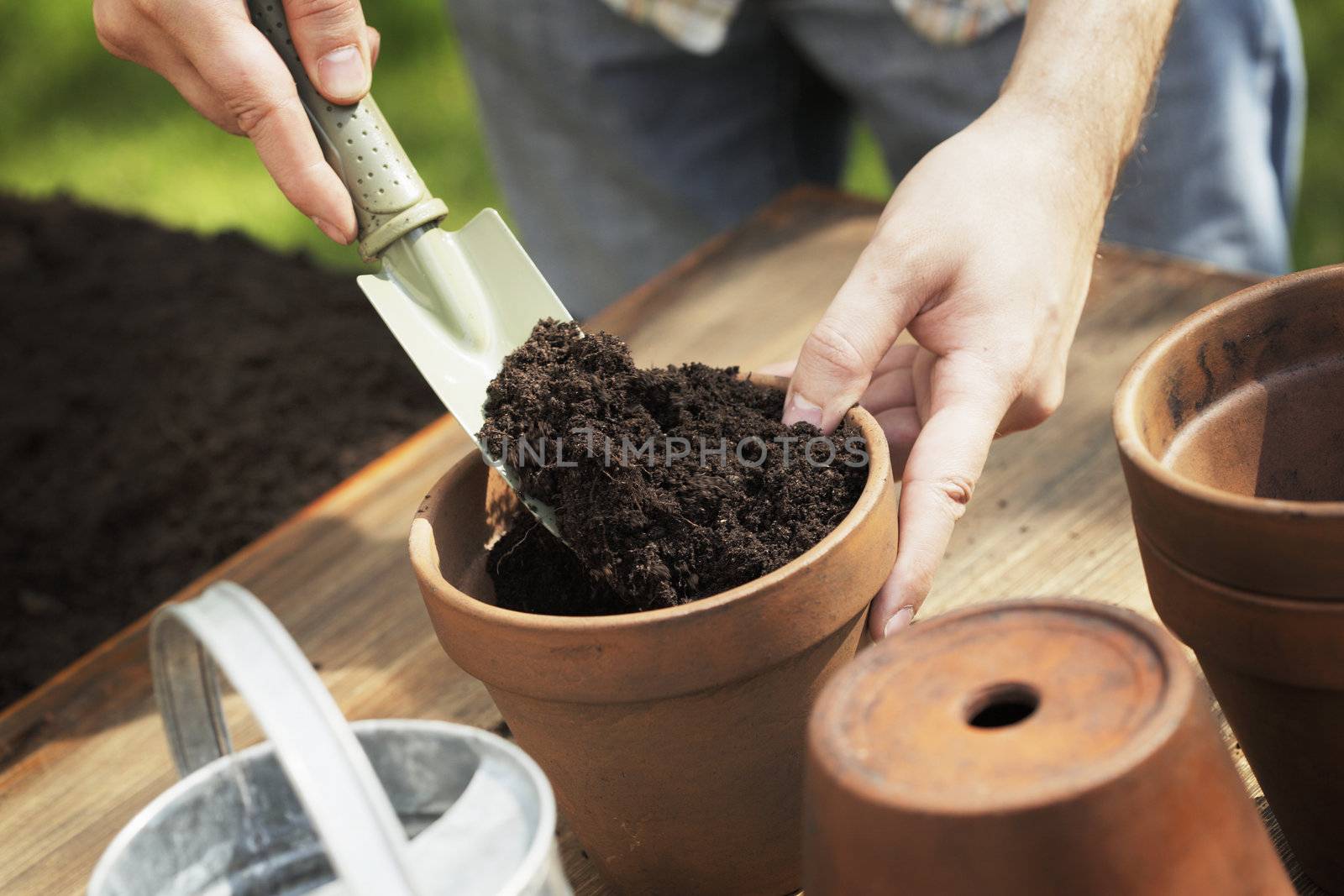 Hands putting soil to a clay flower pot