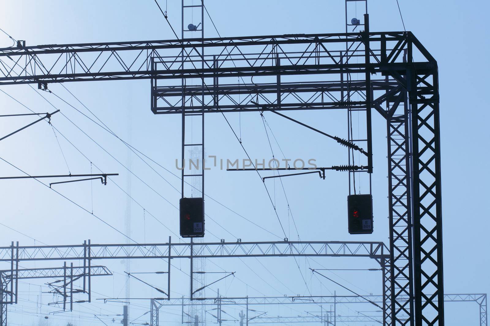 Railroad powerline silhouettes against hazy sky.