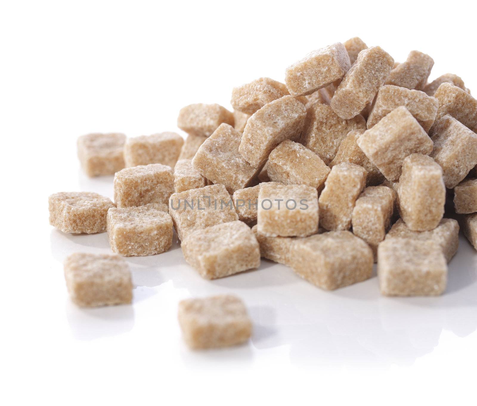 Natural brown sugar cubes on white reflecting background.