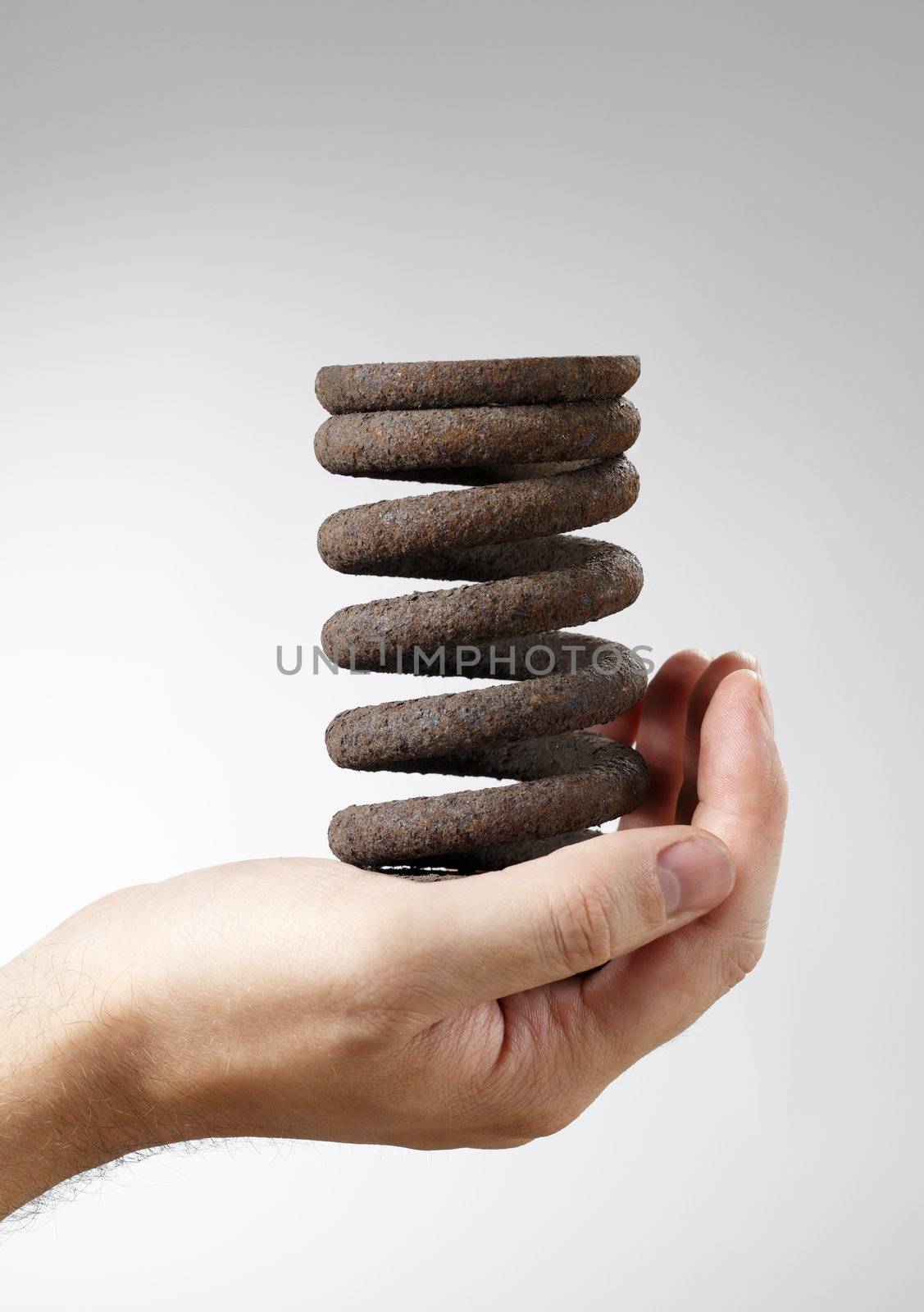 Man holding an old rusty spring in his hand.