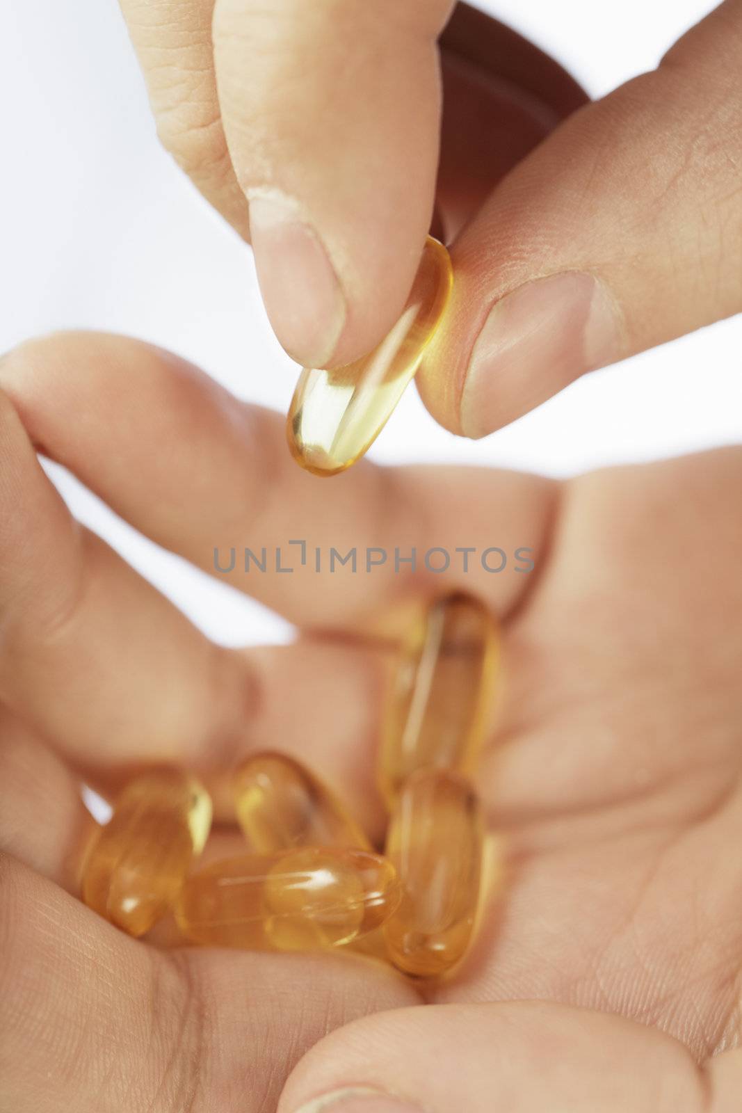 Fingers holding an omega3 fish oil capsule