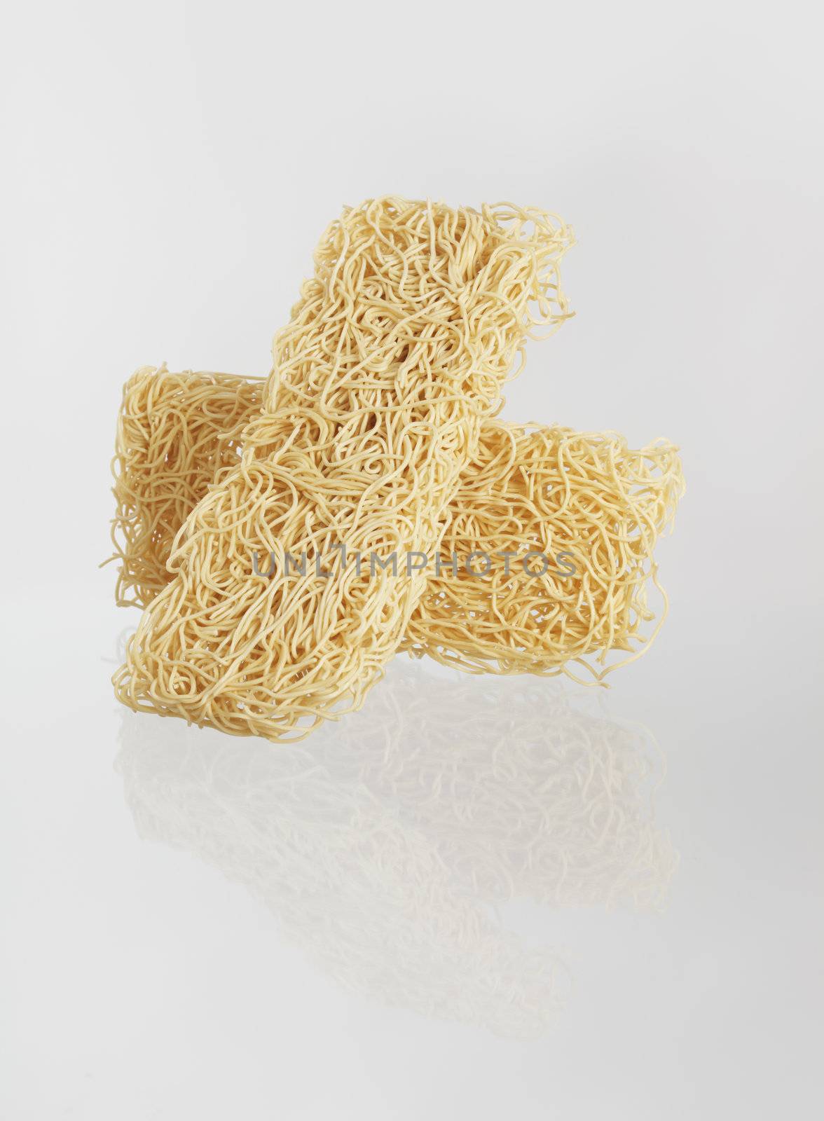 Two blocks of dried asian noodles on reflecting surface.