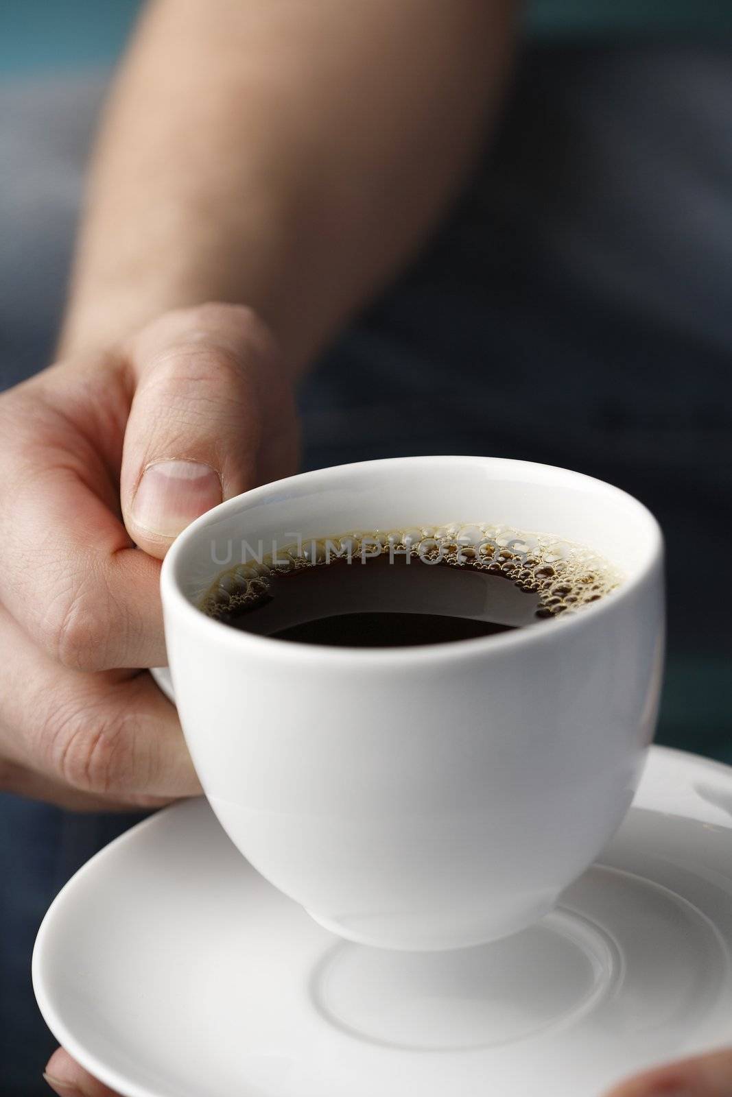 A Hand holding a white cup of black coffee