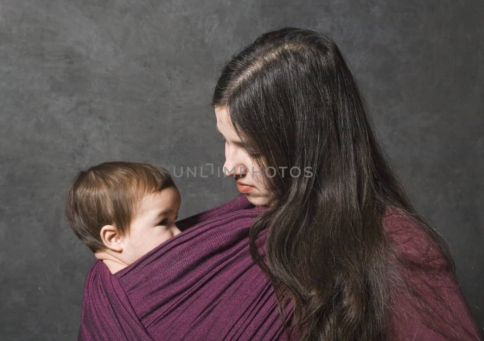 Mother with her daughter in sling, dark background