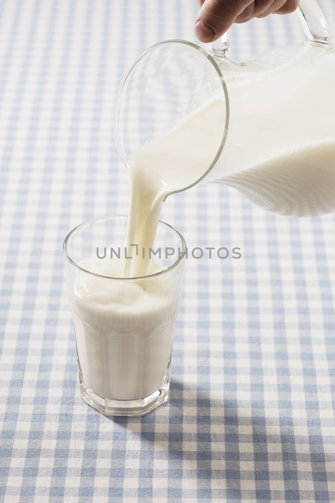 Milk poured from a pitcher to a glass