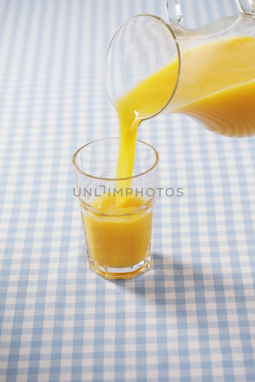 Orange juice being poured from a jug to a glass