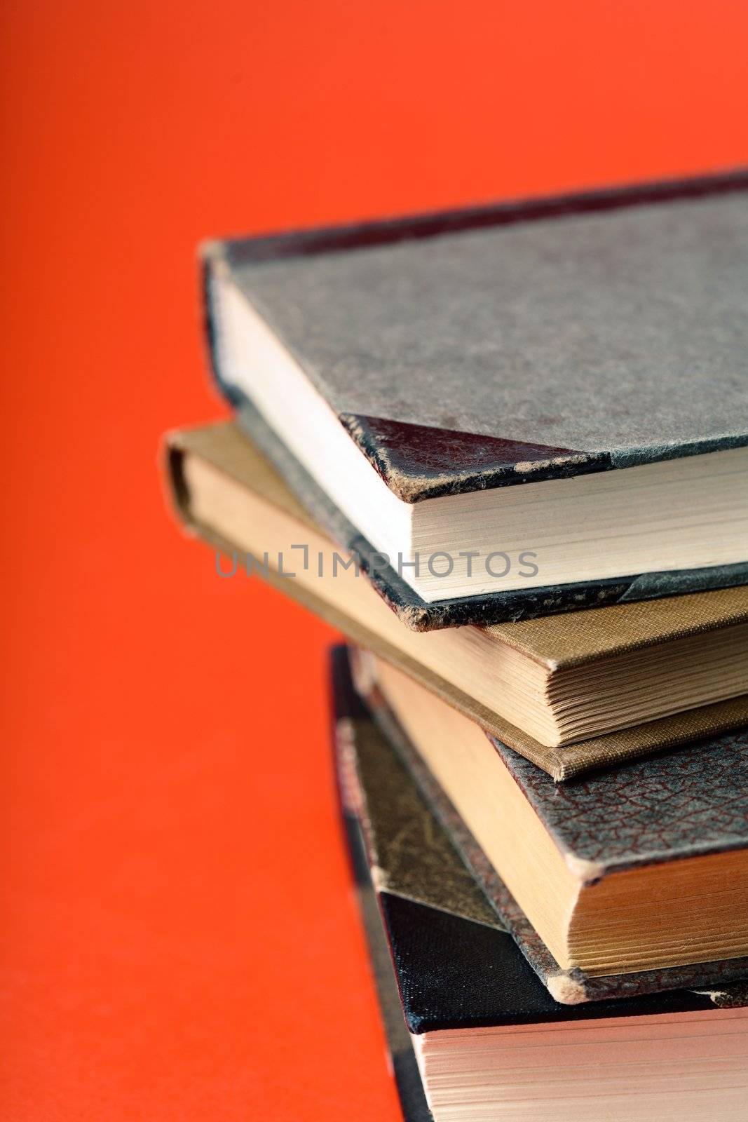 Pile of old books against a red background.
