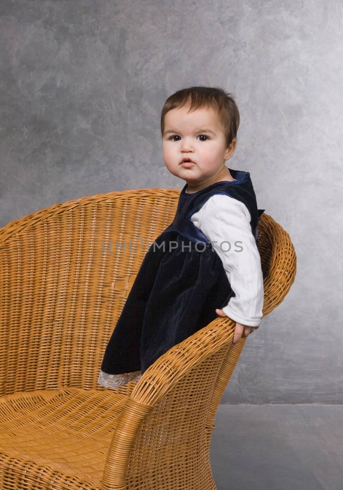 Little girl standing in an armchair, studio shot