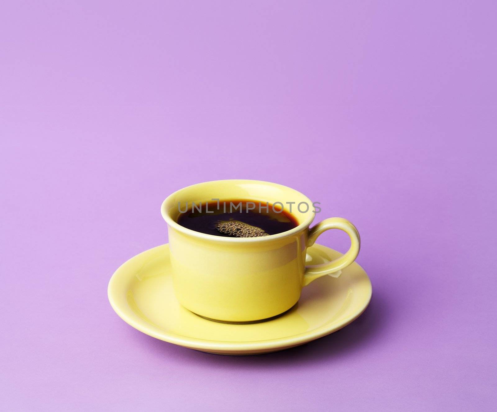 A yellow cup of fresh coffee on a lilac colored background