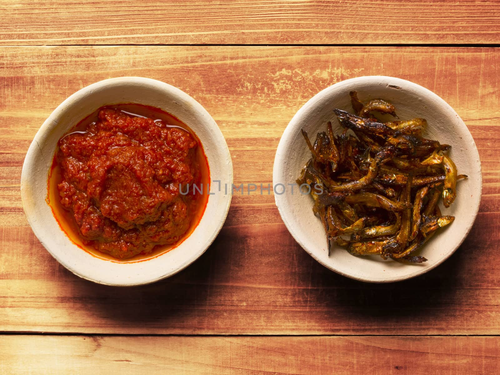 close up of bowls of fried anchovies and sambal chili