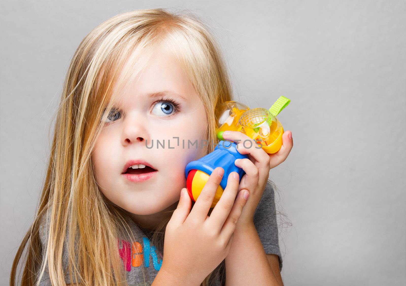 Young girl trying to use a toy hammer as a phone or just having fun playing make believe