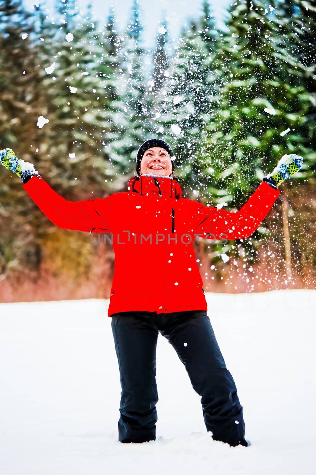 Female throwing a pile of snow up into the air. Female is in focus. by kosmsos111