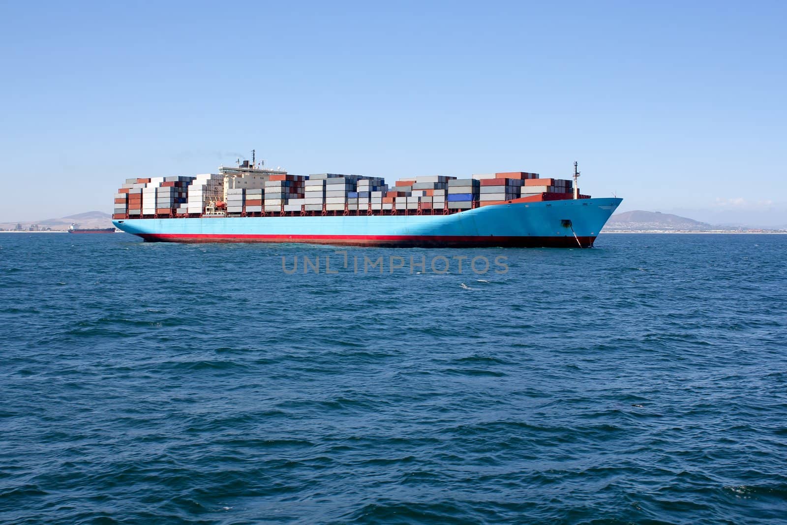 Picture of blue sea with a container ship driving along the horizon