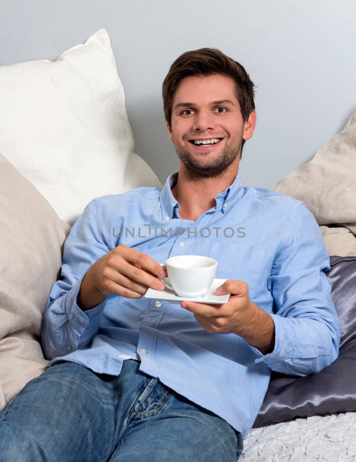 Young brunette man in blue clothing  enjoying a coffeebreak