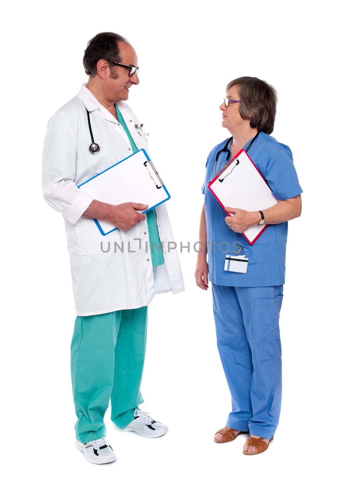 Male and female doctors discussing a case with clipboards in hand