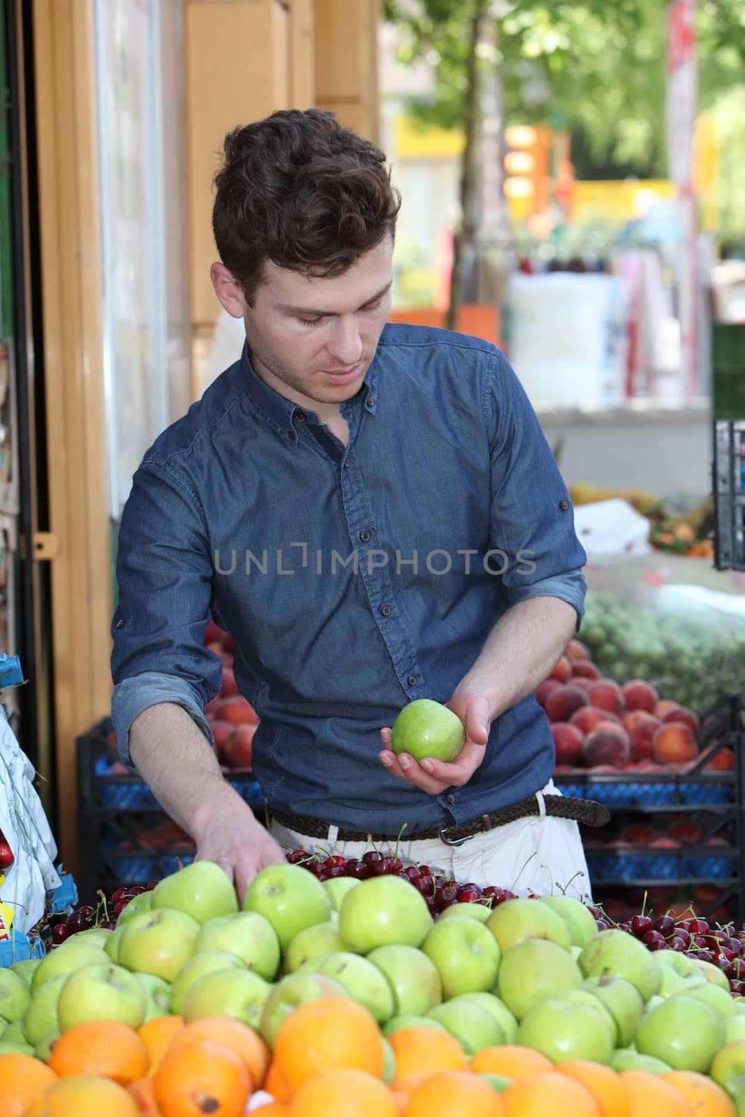 Young handsome customer choosing fruits at grocery store