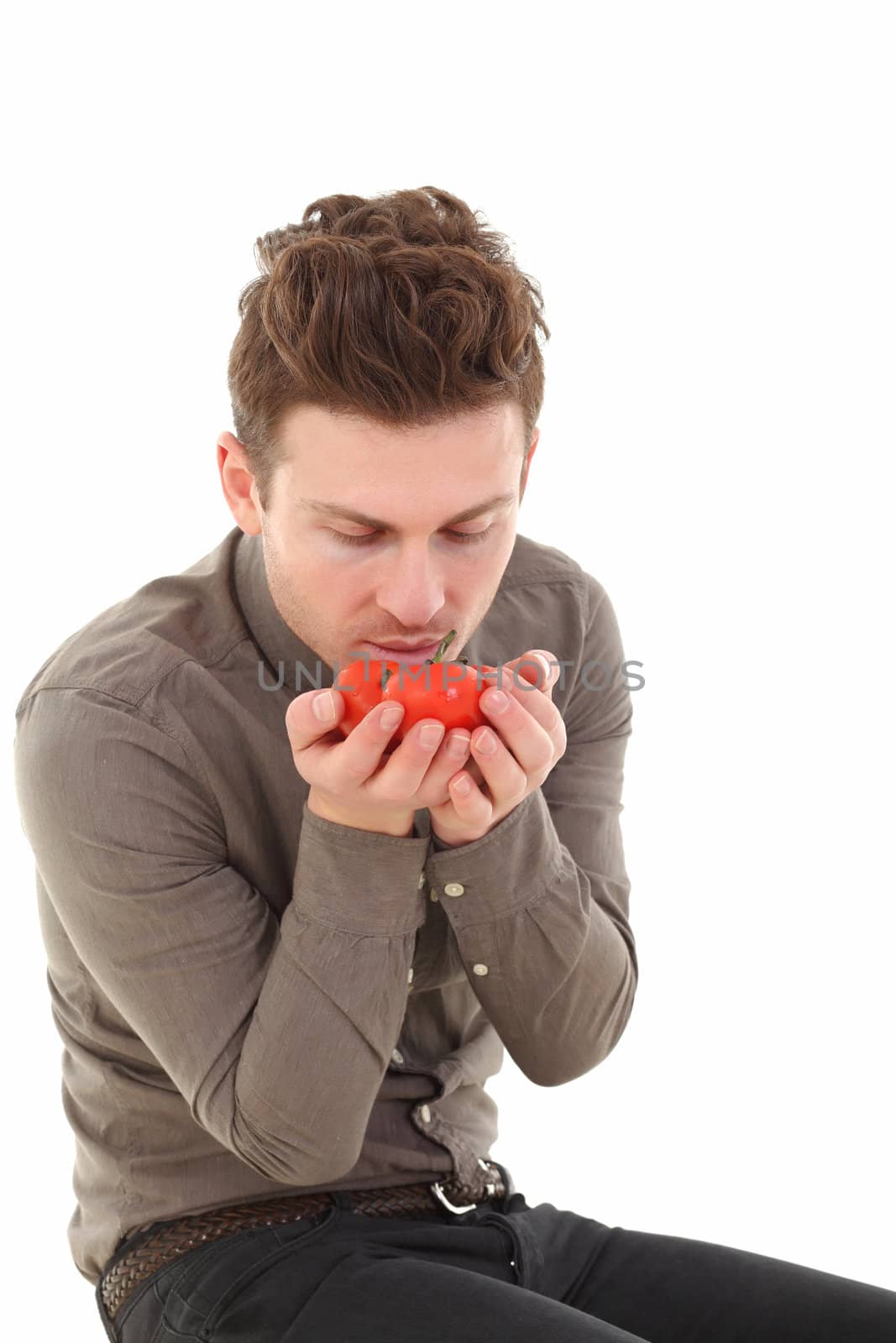 Vertical portrait of young man smelling tomatoes