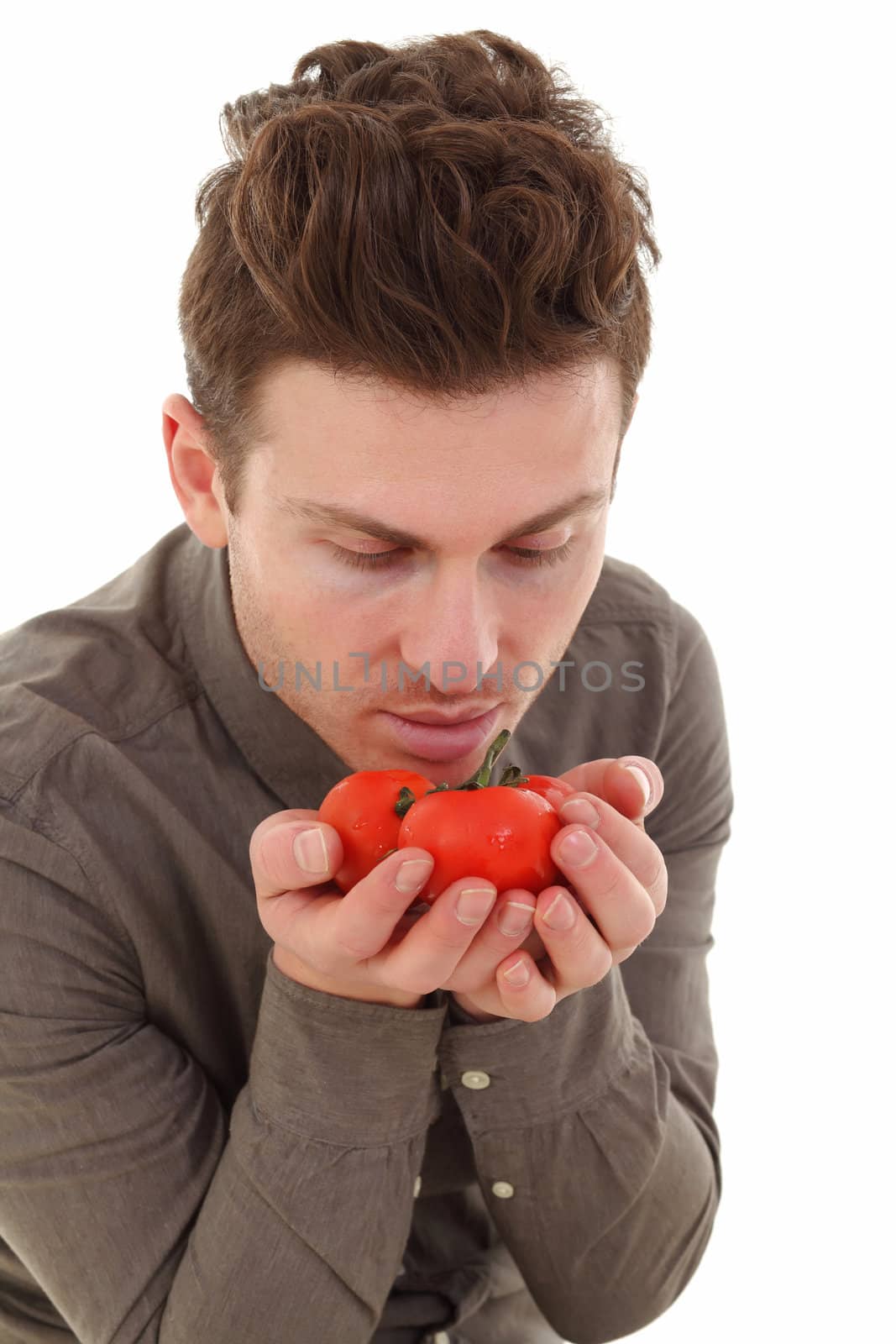 Young man in studio smelling organic tomatoes