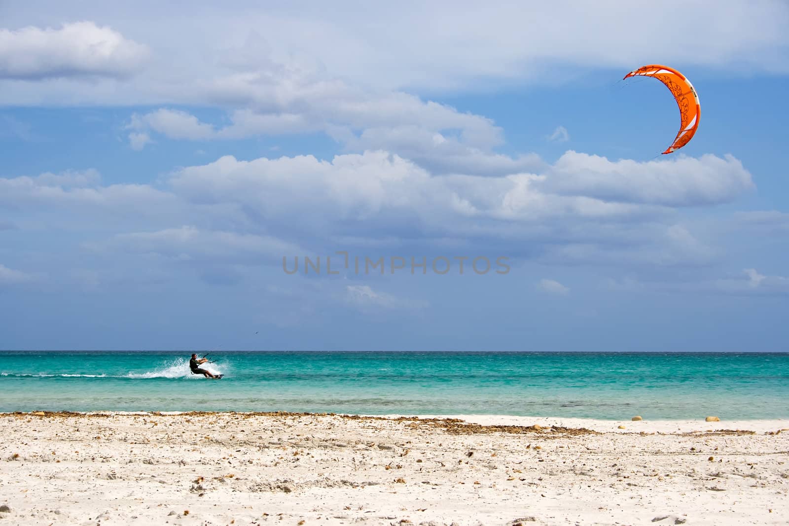 A kitesurfer gliding at high speed around the beach Cinta, Sardinia