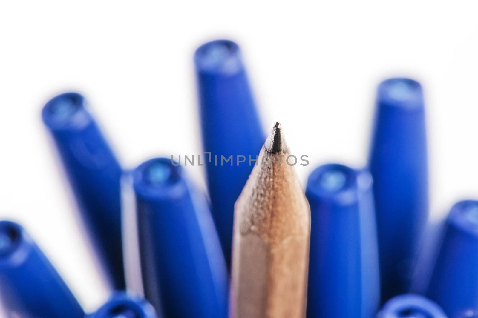 Sharpened pencil between pens in caps.